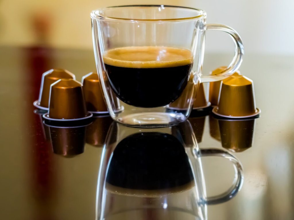 Capsules de café Nespresso scellées autour d'une tasse d'espresso