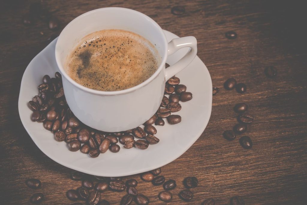 Tasse de café avec de la crema entourée de grains torréfiés