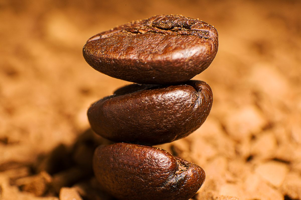 Grains de café entiers posés sur du café moulu