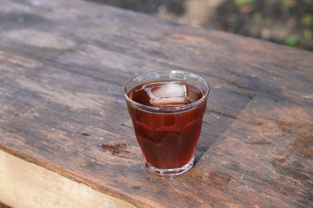 Verre de cold brew avec un glaçon posé sur une planche en bois