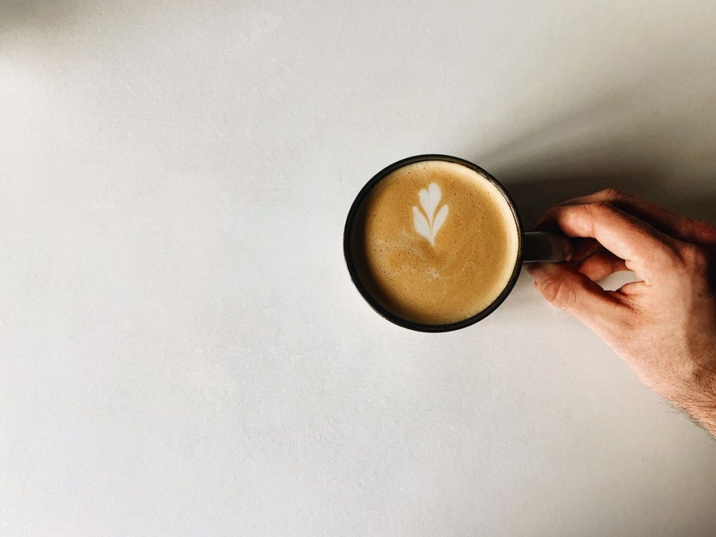 Flat white tenu en main avec latte art