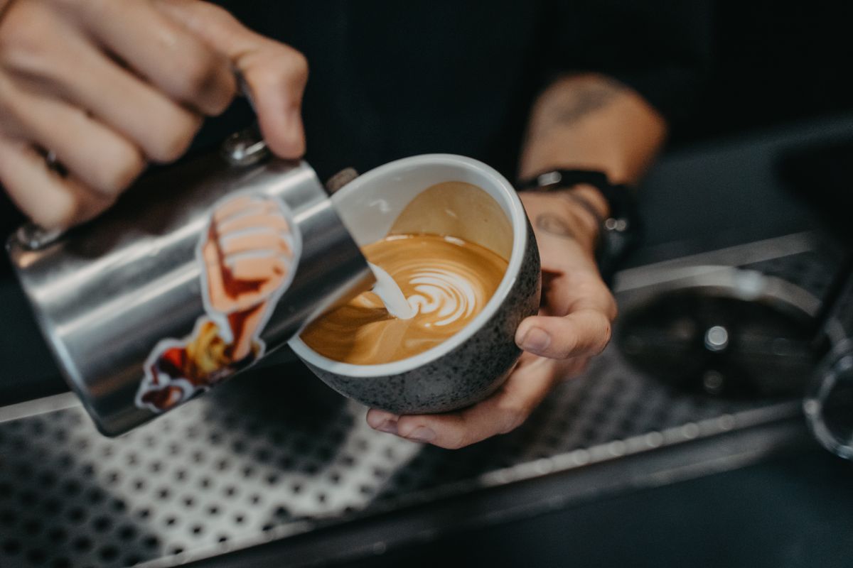 Barista versant du lait pour un latte art rosetta